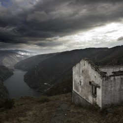  Uno de los barracones de la Paciega, en primer término, con el embalse de Grandes de Salime al fondo