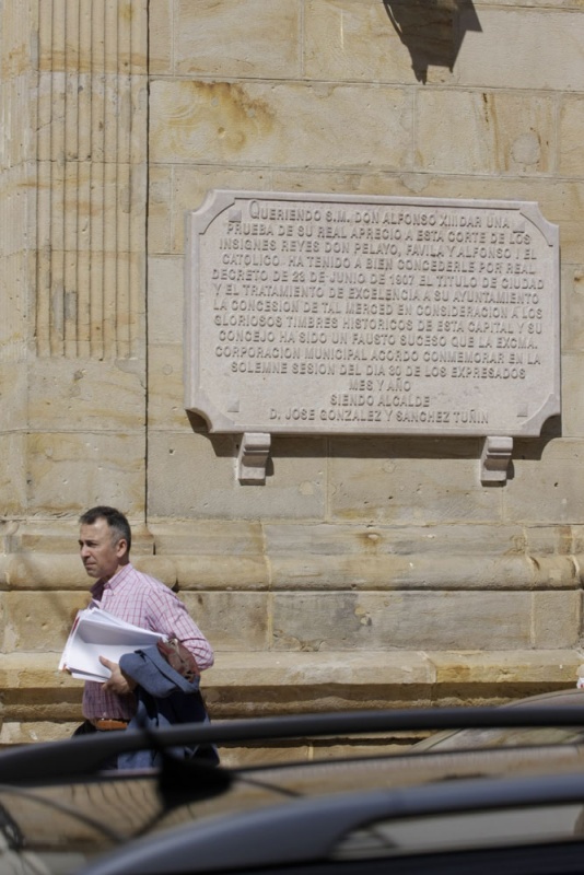 Un transeúnte pasa ante la placa que, en la fachada del ayuntamiento, recuerda la concesión del título de ciudad a Cangas de Onís, en 1907.