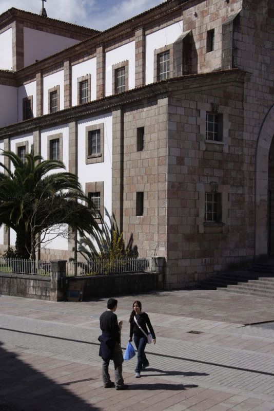 Dos personas, ante la fachada de la iglesia de Cangas de Onís.