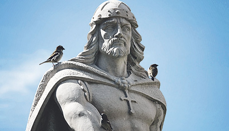 Tres pájaros se posan sobre la estatua de Pelayo, en la plaza de la iglesia