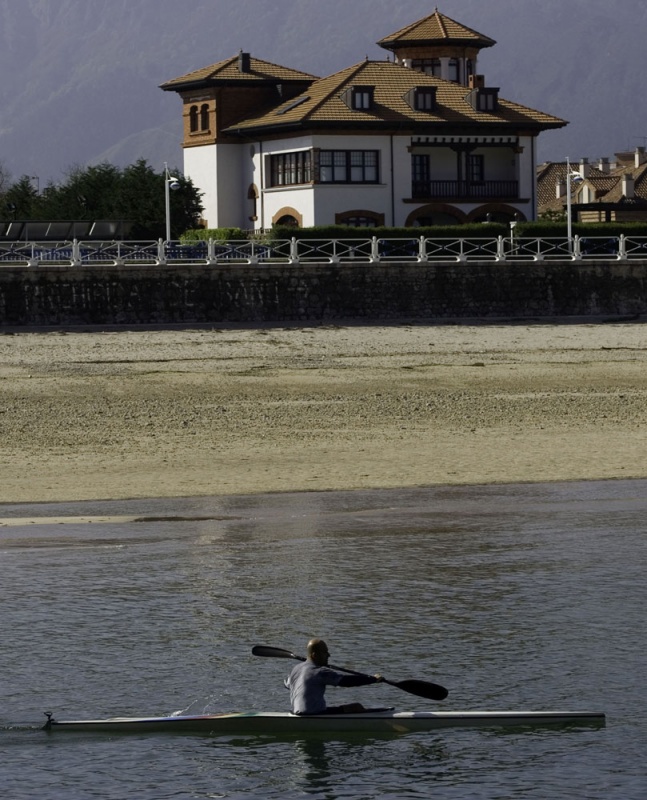 Un piragüista pasa ante uno de los palacetes de la playa de Santa Marina.