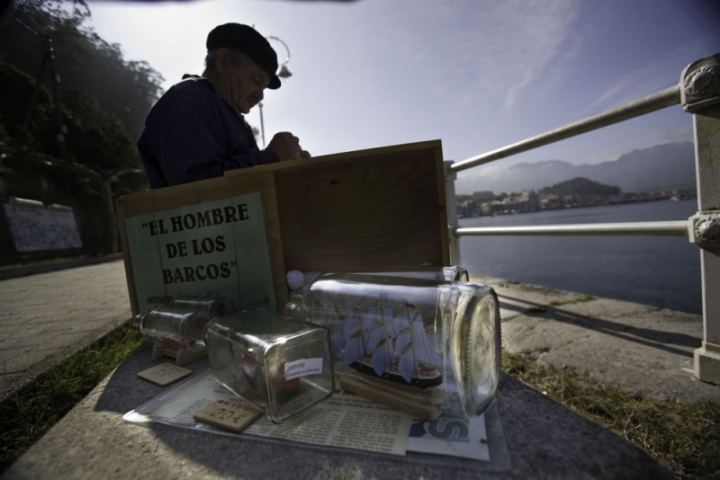 El artesano Enrique Garrote mete barcos en botellas para vender a los turistas en el puerto.