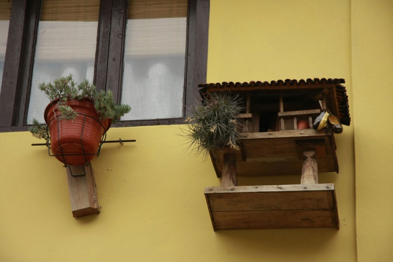 Un hórreo en miniatura, colgado de una fachada en el barrio de Pumarín de Caravia Alta.