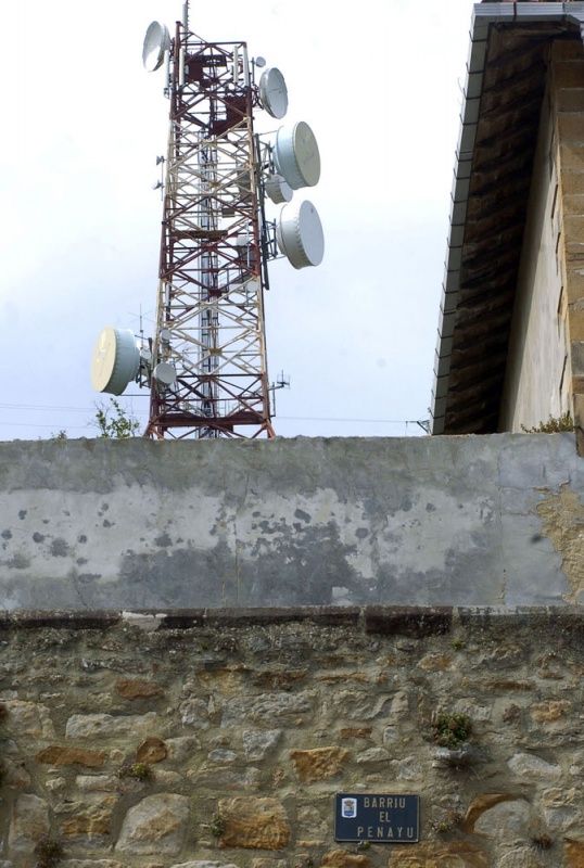 Una antena de telefonía se asoma tras un muro del barrio de El Penayu.