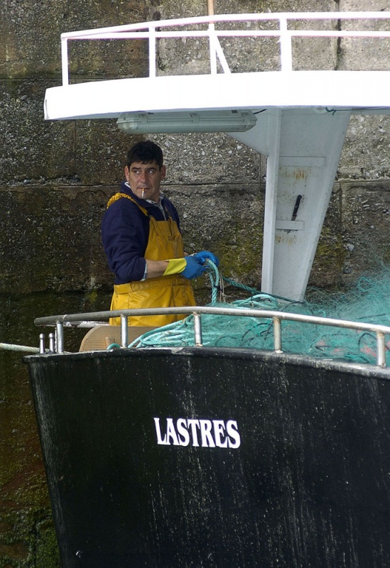 Un marinero, trajinando en un barco en el puerto de Lastres.