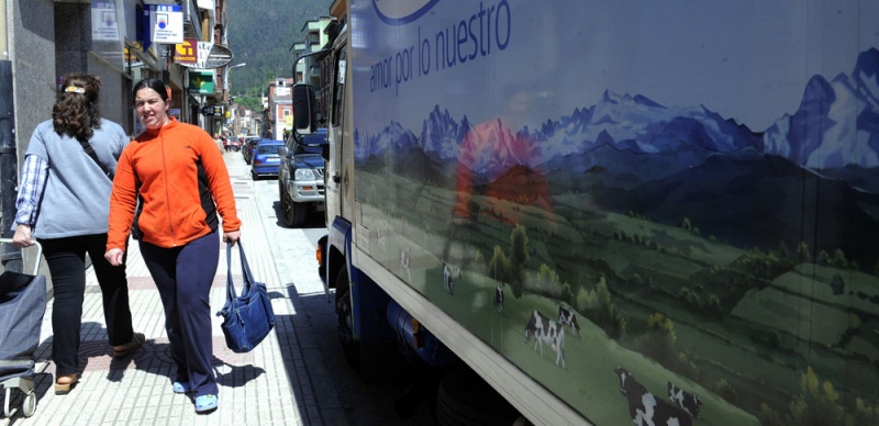 Dos mujeres pasan junto a un camión de reparto en la calle Covadonga.