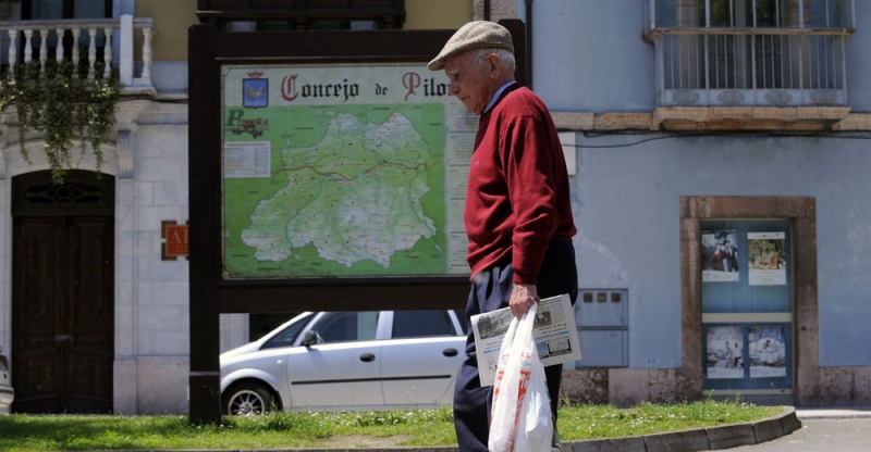 Un hombre pasa por delante de un panel informativo del concejo de Piloña, en la plaza del Ganado.