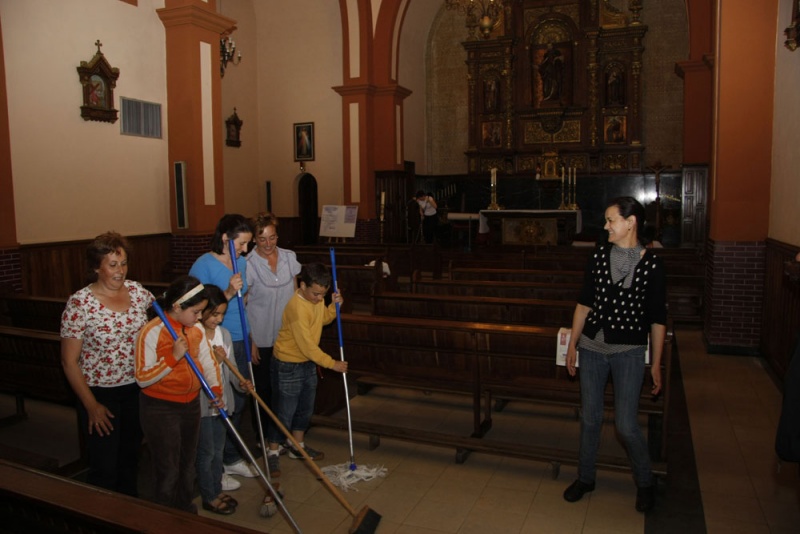 Mujeres y niños limpian la iglesia de Villamayor.
